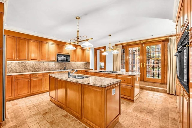 kitchen with black appliances, a center island with sink, brown cabinetry, decorative backsplash, and a sink