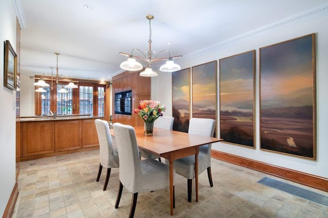 dining area with crown molding, a notable chandelier, and light floors