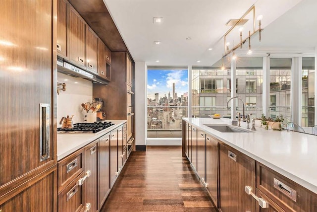 kitchen with stainless steel gas cooktop, a city view, light countertops, dark wood-style floors, and a sink