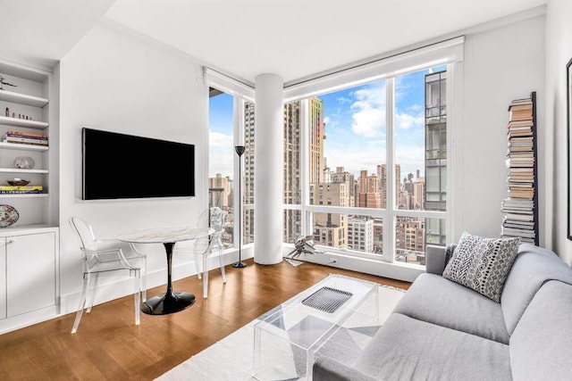 living room featuring floor to ceiling windows, built in shelves, and wood finished floors