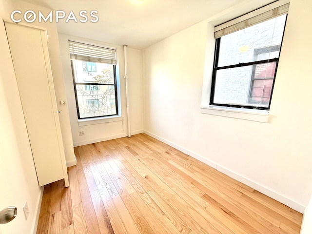 unfurnished room with baseboards and wood-type flooring