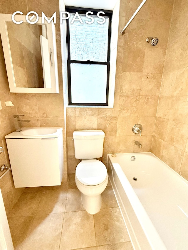 bathroom featuring tile patterned floors, toilet, a sink, tile walls, and bathtub / shower combination