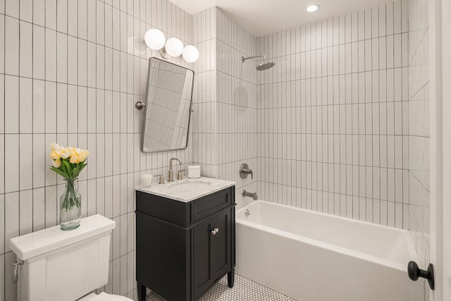 bathroom featuring tile patterned floors, toilet, tile walls, shower / bath combination, and vanity