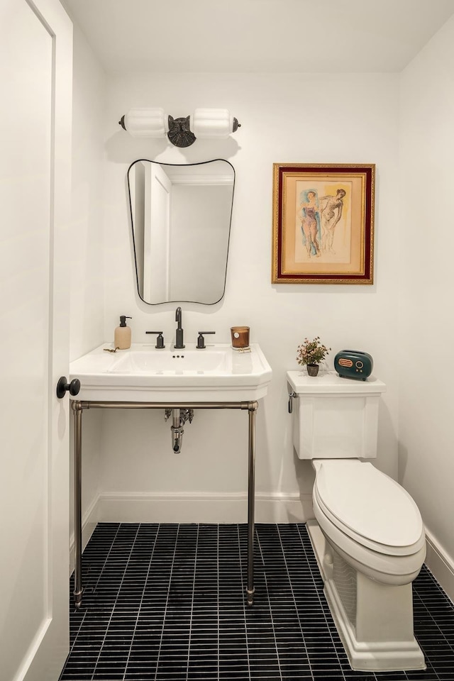 bathroom featuring tile patterned floors, toilet, baseboards, and a sink