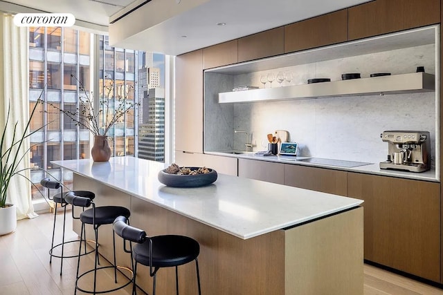 kitchen with open shelves, light countertops, black electric stovetop, tasteful backsplash, and a center island