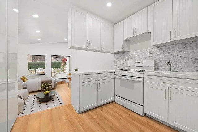 kitchen with white range with gas cooktop, light wood-style flooring, light countertops, and a peninsula