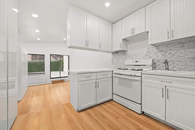 kitchen featuring a peninsula, gas range gas stove, light countertops, and light wood finished floors