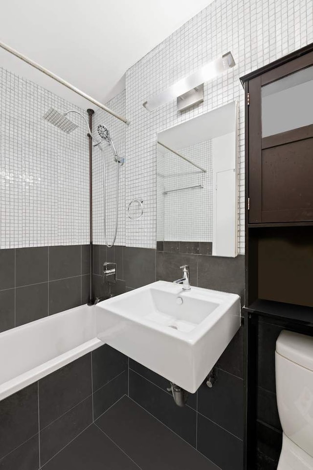 bathroom with toilet, a sink, tasteful backsplash, tile walls, and tiled shower