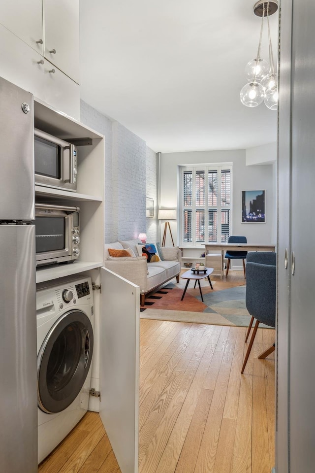 interior space featuring a notable chandelier, laundry area, light wood-style flooring, and washer / clothes dryer