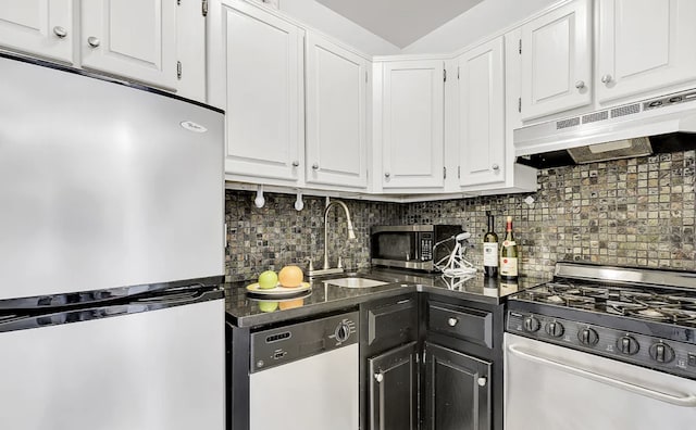 kitchen with dark countertops, under cabinet range hood, stainless steel appliances, white cabinetry, and a sink