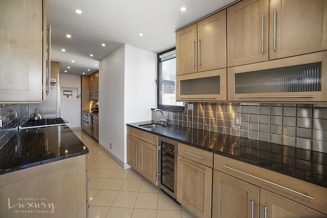 kitchen with beverage cooler, light tile patterned floors, dark stone countertops, gas cooktop, and a sink