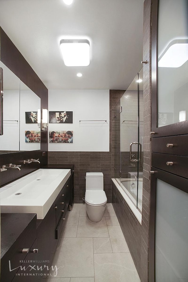 full bath with vanity, tile patterned flooring, tile walls, toilet, and tiled shower / bath