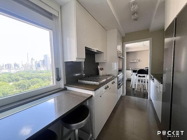 kitchen featuring cooktop, dark countertops, white cabinets, and freestanding refrigerator