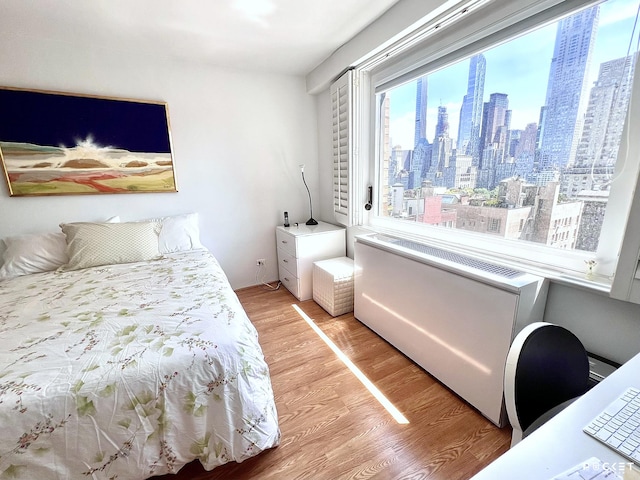 bedroom featuring a city view and light wood-style flooring