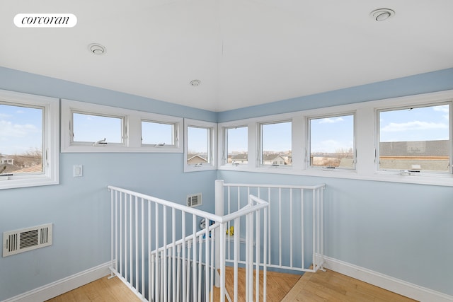 staircase featuring a wealth of natural light, visible vents, and wood finished floors