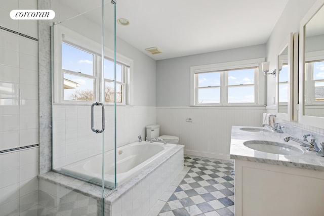 bathroom with a relaxing tiled tub, plenty of natural light, and a sink