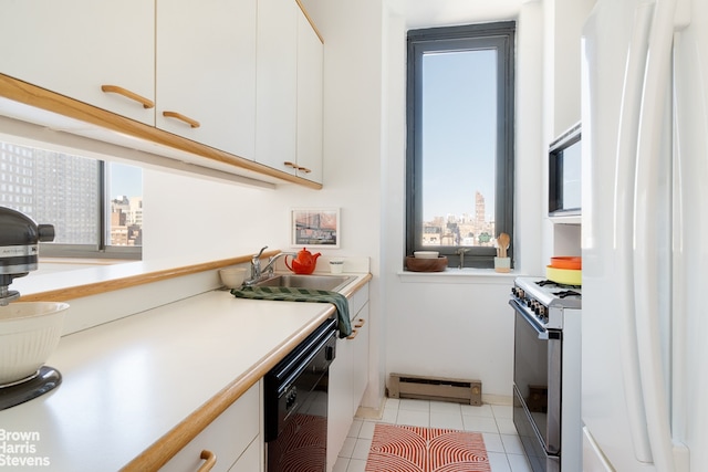 kitchen with a baseboard heating unit, black dishwasher, range with gas stovetop, freestanding refrigerator, and a view of city