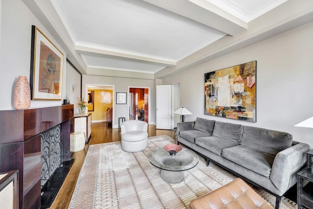 living area with beam ceiling, crown molding, baseboards, and wood finished floors