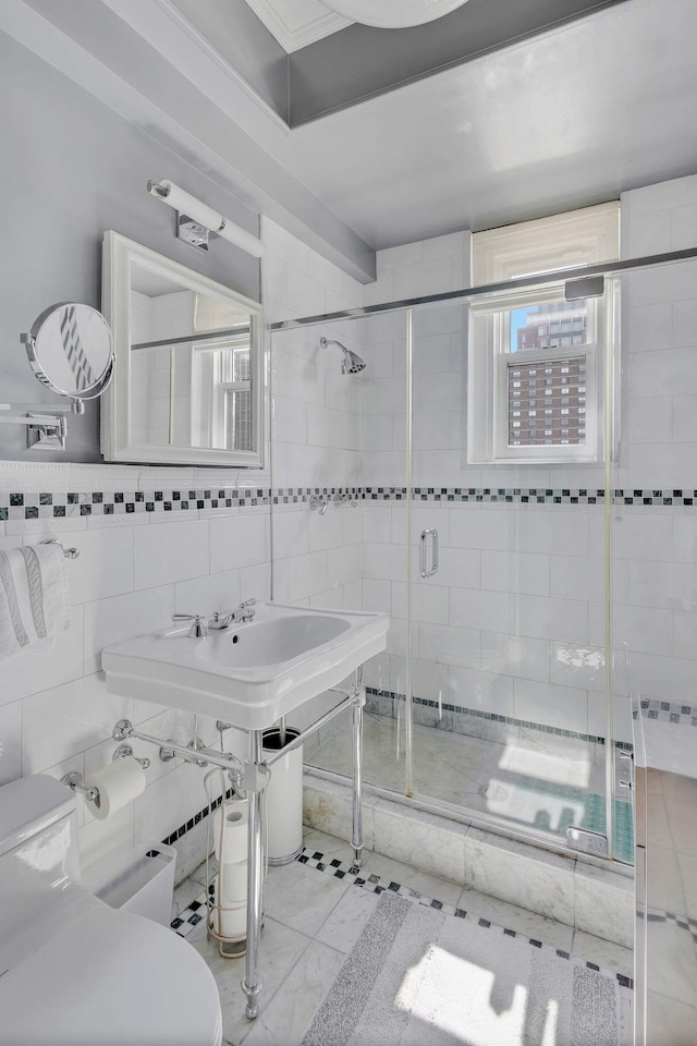 bathroom with tile walls, toilet, a stall shower, and a wealth of natural light