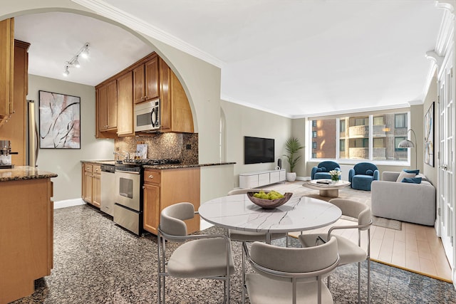 61 W 62nd St Unit 12G, New York City, NY 10023 - kitchen featuring stainless steel appliances, arched walkways, baseboards, decorative backsplash, and dark stone counters