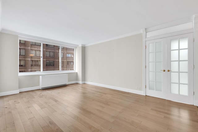 spare room with radiator heating unit, light wood finished floors, and ornamental molding