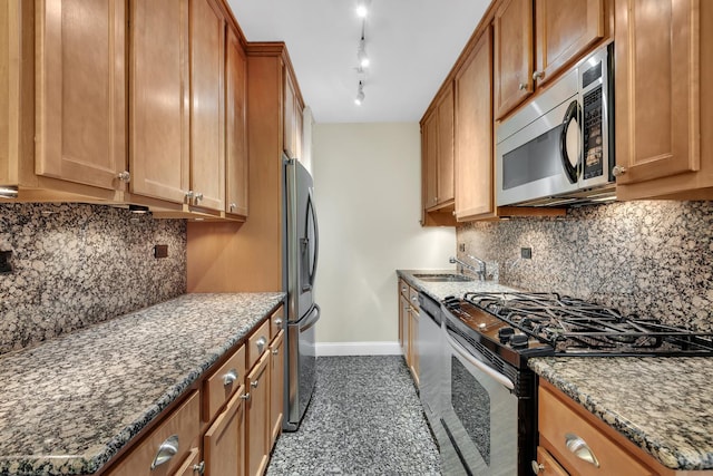 kitchen featuring brown cabinets, dark stone counters, appliances with stainless steel finishes, decorative backsplash, and baseboards