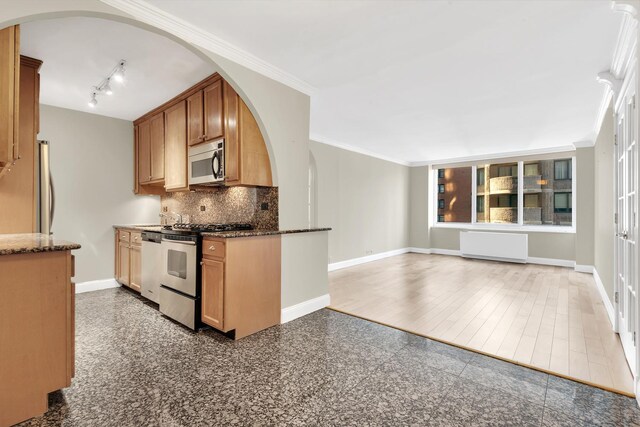 61 W 62nd St Unit 12G, New York City, NY 10023 - kitchen with appliances with stainless steel finishes, arched walkways, baseboards, tasteful backsplash, and crown molding