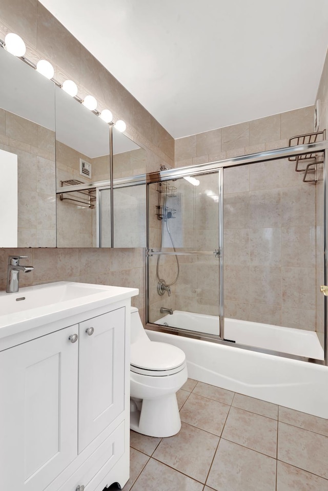 full bath with tile walls, toilet, tile patterned floors, vanity, and enclosed tub / shower combo