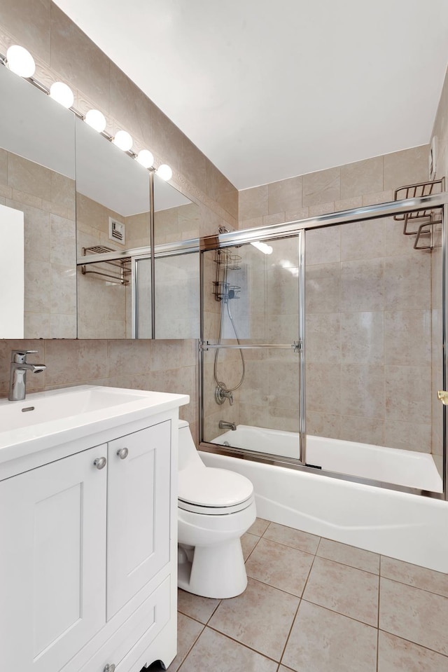 61 W 62nd St Unit 12G, New York City, NY 10023 - full bathroom featuring vanity, combined bath / shower with glass door, tile walls, tile patterned floors, and toilet