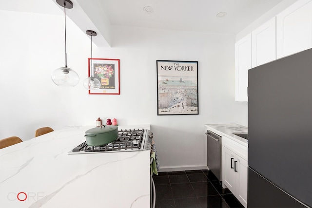 kitchen featuring light stone countertops, white cabinetry, dark tile patterned flooring, freestanding refrigerator, and stainless steel dishwasher