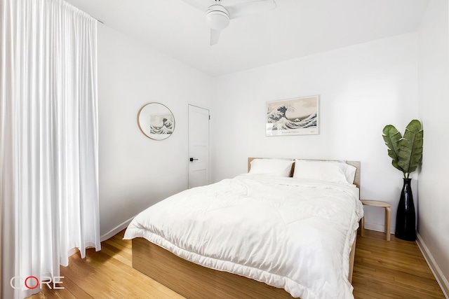 bedroom featuring baseboards, wood finished floors, and a ceiling fan