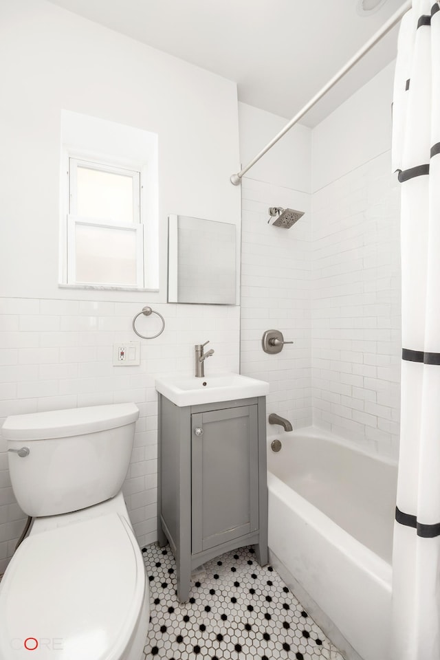 bathroom featuring tub / shower combination, toilet, vanity, tile patterned floors, and tile walls