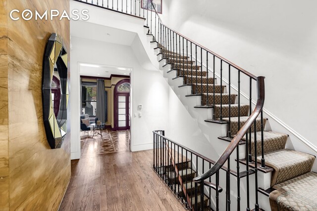 foyer entrance with baseboards, a high ceiling, wood finished floors, and stairway