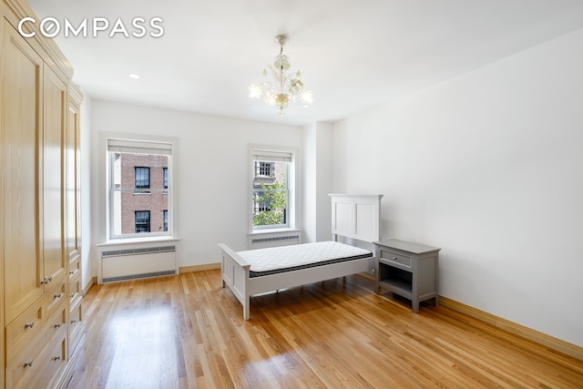 unfurnished bedroom featuring a notable chandelier, baseboards, radiator heating unit, and light wood-style floors