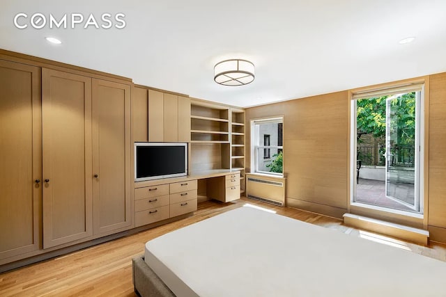 bedroom with radiator heating unit, built in desk, recessed lighting, light wood-style flooring, and access to outside