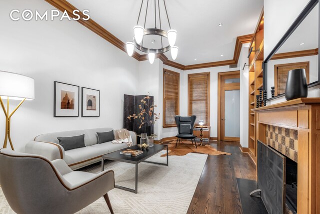 living room featuring baseboards, ornamental molding, a fireplace, and dark wood-type flooring