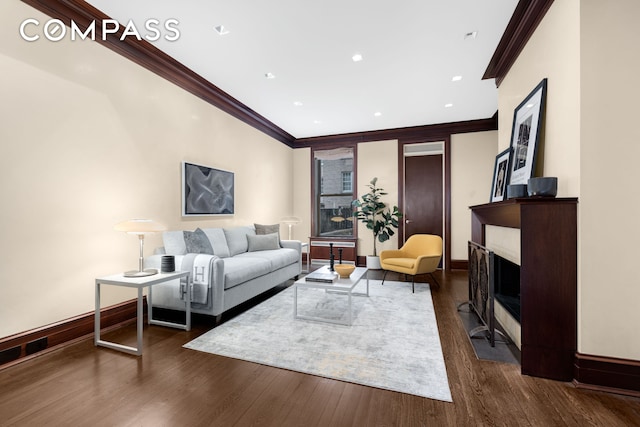 living room featuring dark wood-style floors, baseboards, a fireplace with flush hearth, and ornamental molding