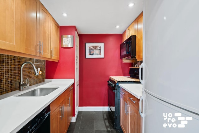 kitchen with baseboards, a sink, decorative backsplash, black appliances, and light countertops