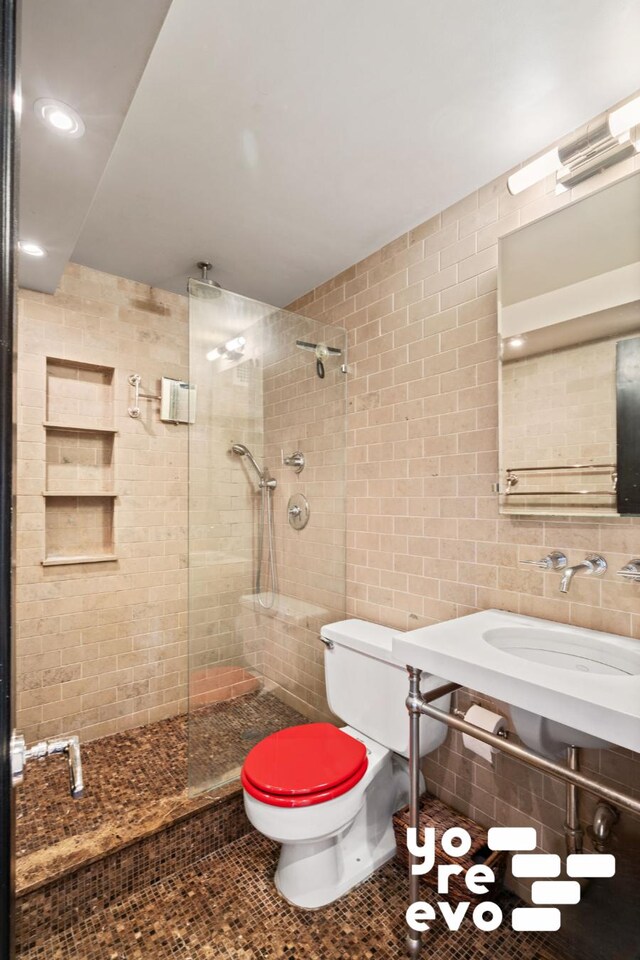 full bath with tile walls, toilet, walk in shower, a sink, and tile patterned floors