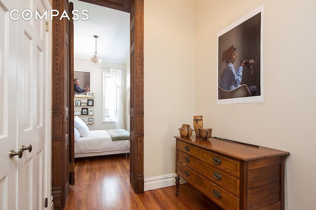 hallway with dark wood-type flooring, baseboards, and ornamental molding