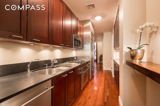 kitchen with baseboards, visible vents, a sink, light wood-style floors, and appliances with stainless steel finishes