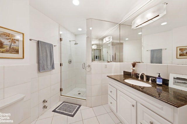 bathroom featuring tile patterned flooring, a stall shower, tile walls, and vanity