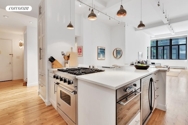 kitchen with stainless steel range, track lighting, visible vents, and light wood-type flooring