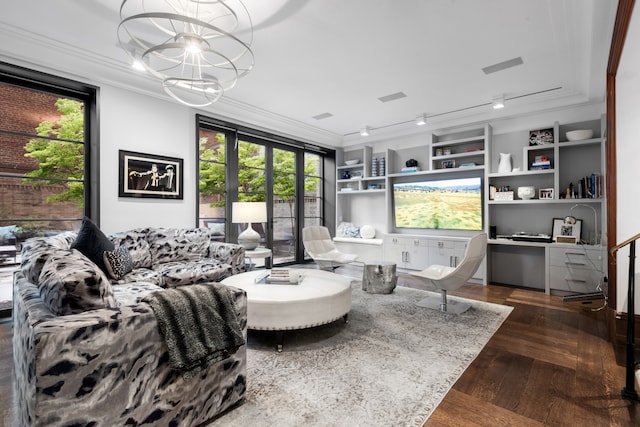 living room featuring dark wood-type flooring, built in shelves, ornamental molding, and an inviting chandelier