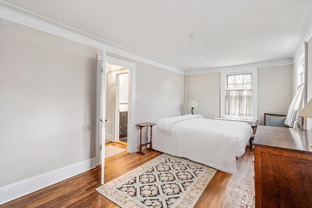 bedroom featuring crown molding, baseboards, and wood finished floors