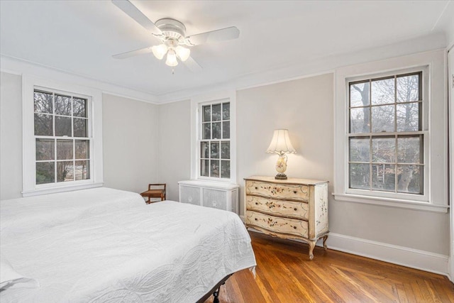 bedroom with ceiling fan, baseboards, wood finished floors, and radiator heating unit