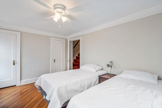 bedroom featuring a ceiling fan, crown molding, wood finished floors, and baseboards