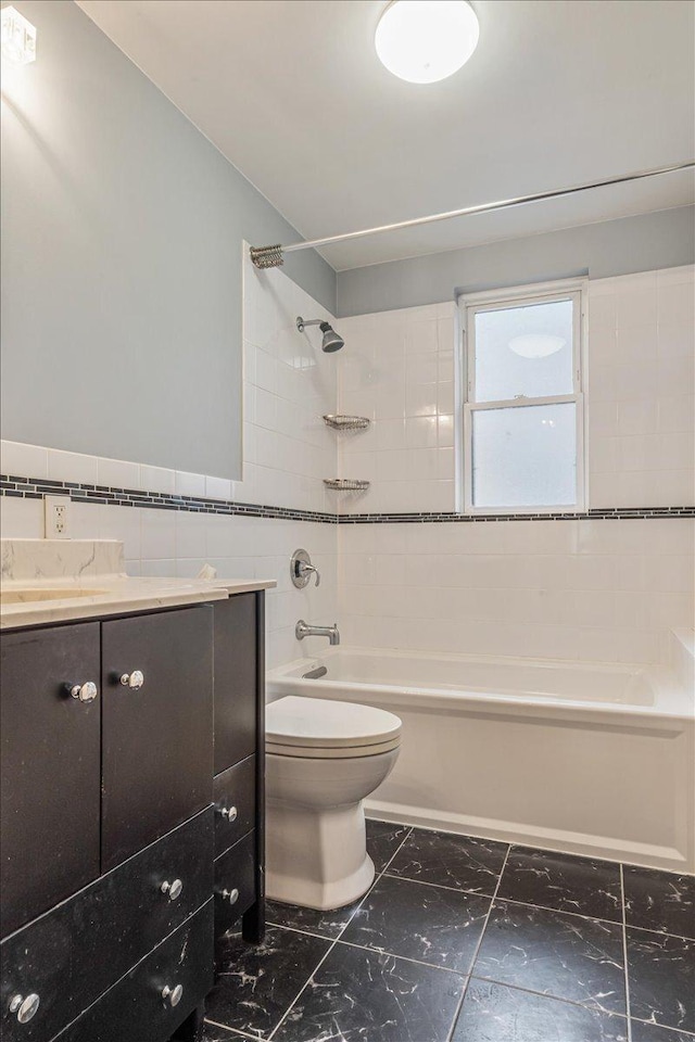 full bath featuring toilet, vanity, bathing tub / shower combination, marble finish floor, and tile walls