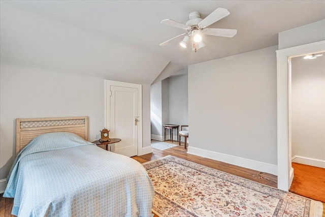 bedroom with ceiling fan, baseboards, lofted ceiling, and wood finished floors