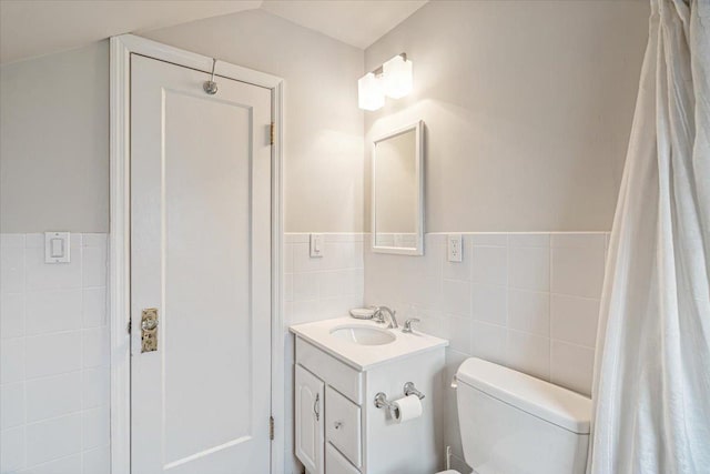 bathroom featuring vanity, tile walls, toilet, and a wainscoted wall